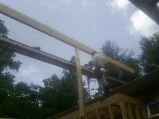Carpenter setting a ridge beam over a new addition frame — Ice Dam Removal by Roofing Brothers in Adair