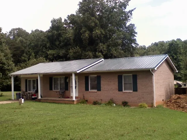 Gray metal roof on a brick ranch house with a side carport in Adair