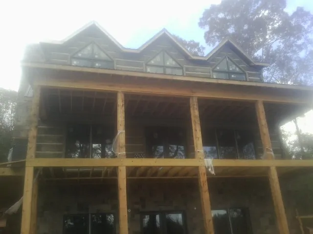 Dormers and porch framing on a large log home under construction — Roof Coating work by our crew in Adair