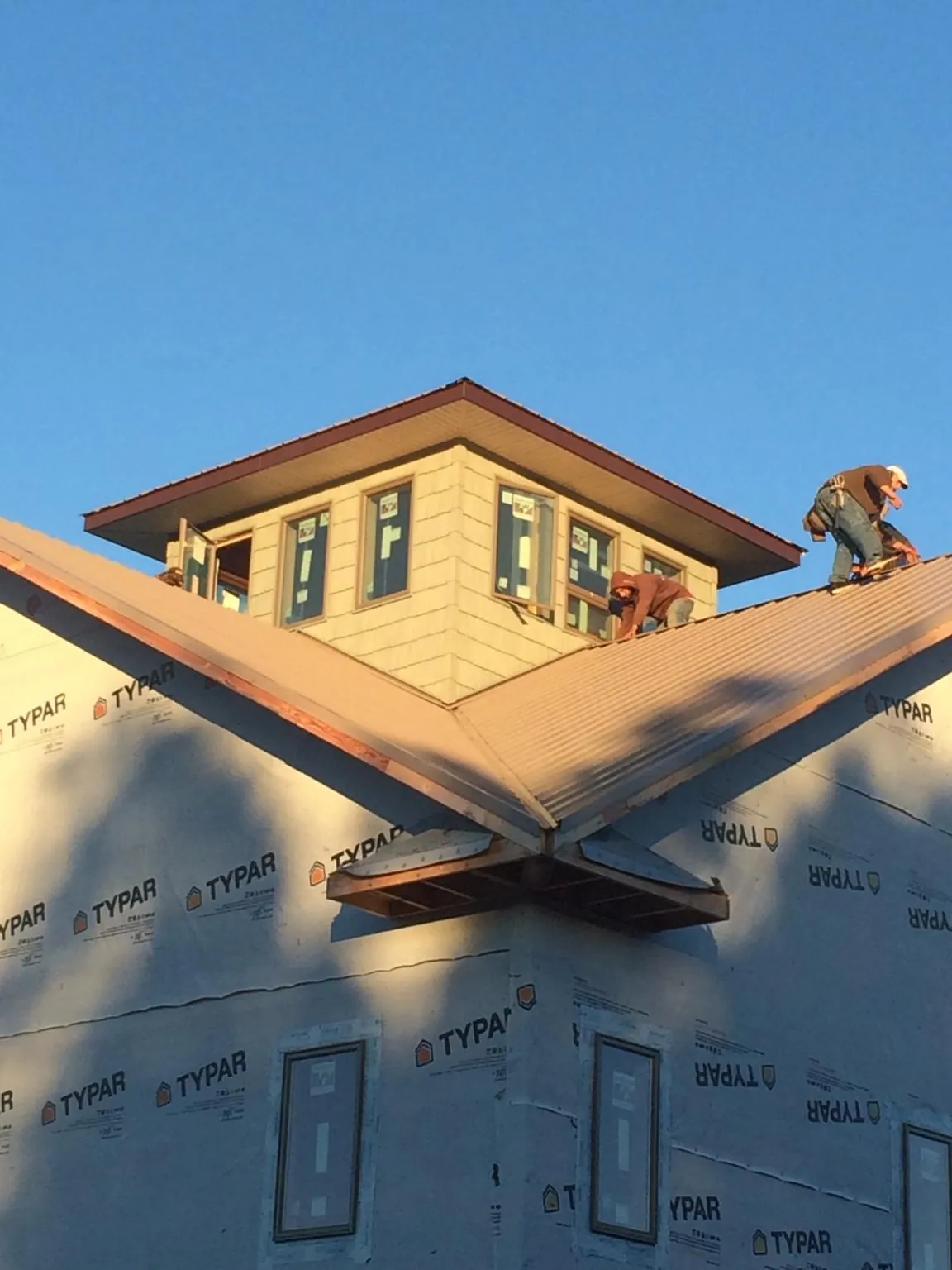 Roofers working around a rooftop cupola on a new metal roof at sunset — Roof Waterproofing in Adair by Roofing Brothers